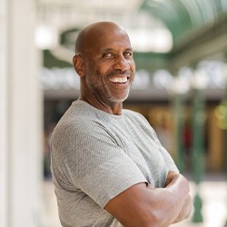 Man in gray shirt smiling outside