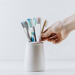 Hand reaches for toothbrush in holder