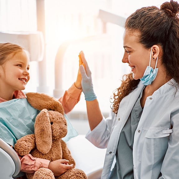 Pediatric dentist in Lancaster high-fiving young patient