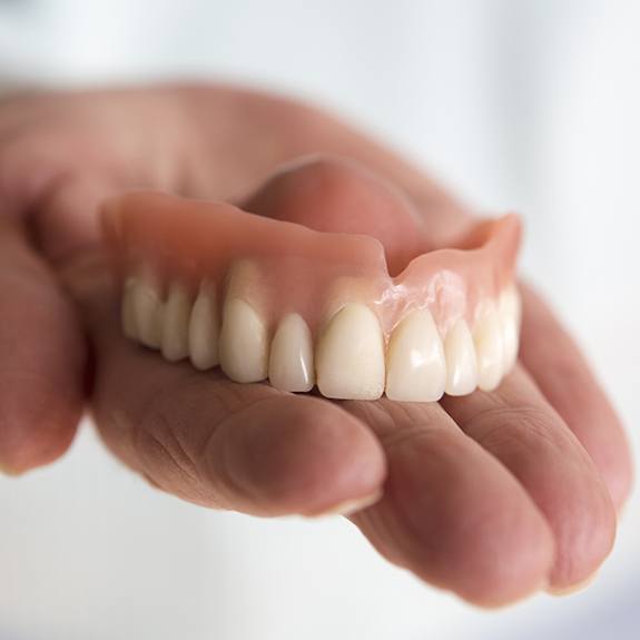 Hand holding a full denture