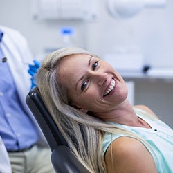 a woman with a new denture smiling in a dental chair