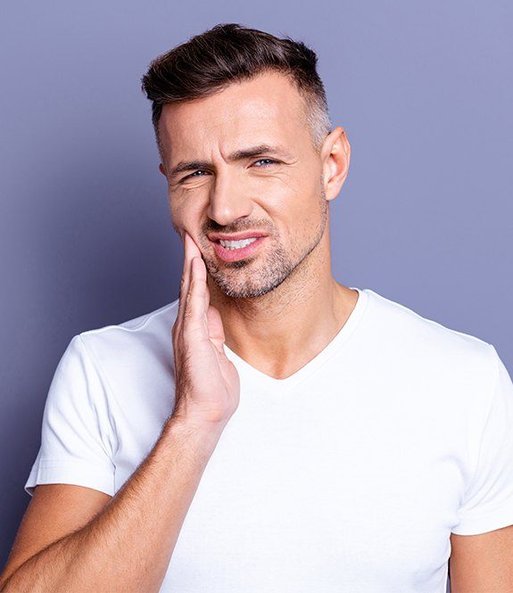 Man in need of emergency dentistry holding cheek