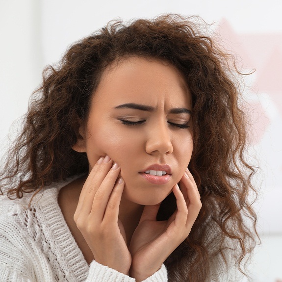 Woman in need of emergency dentistry holding cheeks