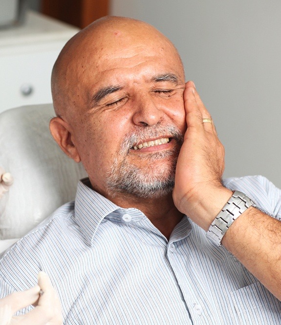 Man holding cheek in pain needs tooth extraction