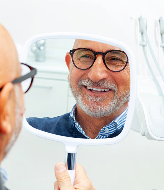 a patient smiling into a handheld mirror