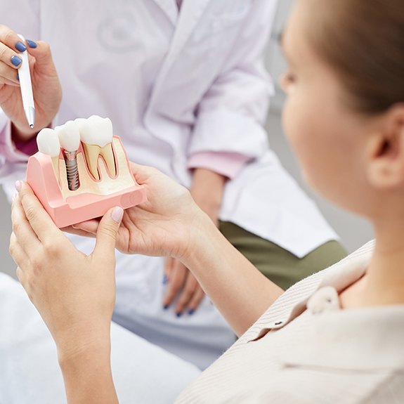 a patient holding a dental implant model