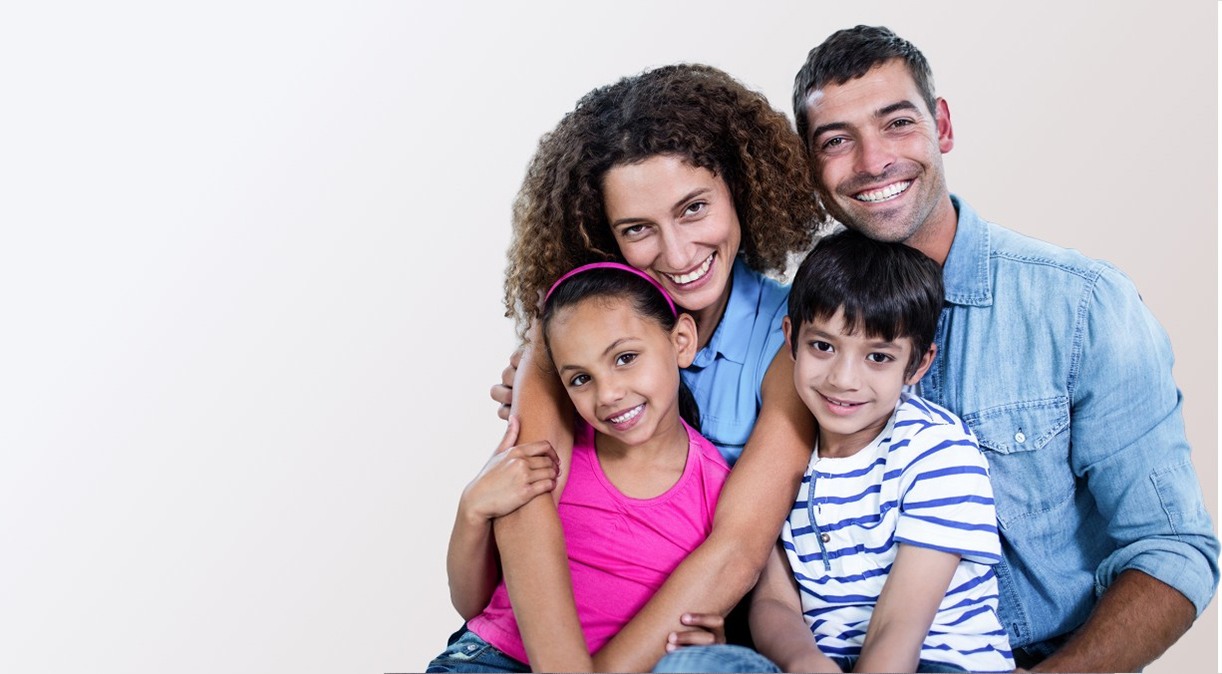 Family of four smiling together thanks to our dentist in Lancaster Texas