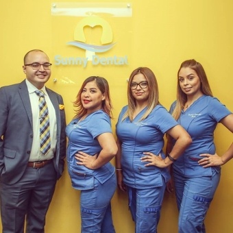 Dentist and team members in front of Sunny dental sign