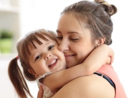 Mother holding child with healthy smile thanks to children's dentistry