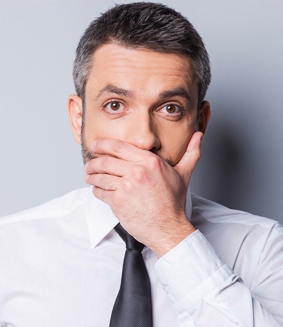 Man with missing teeth hiding his smile