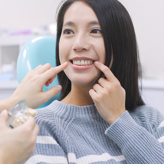 A patient pointing to her smile with a dentist.