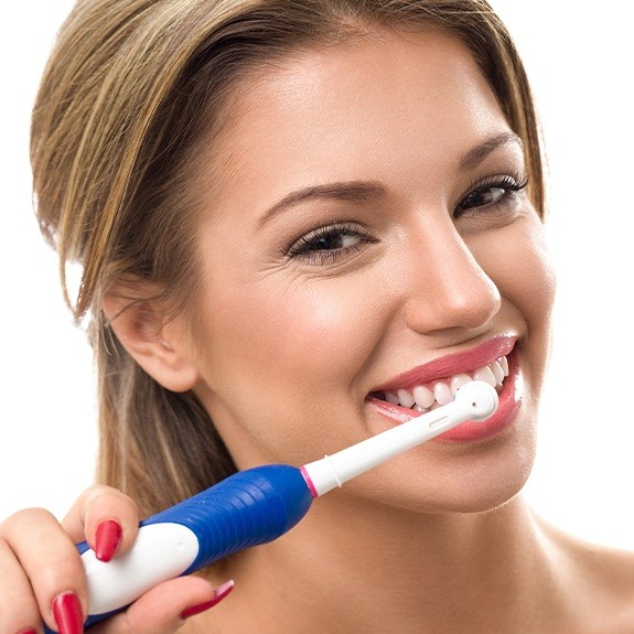 Woman brushing teeth with electric toothbrush