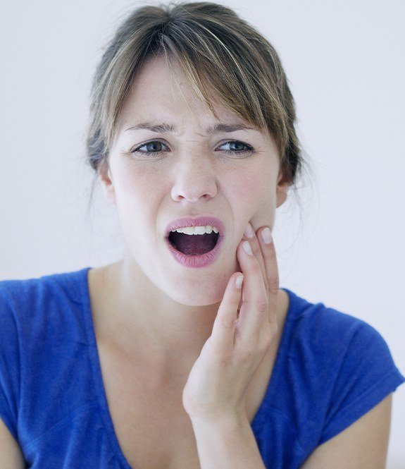 Woman in need of root canal therapy holding cheek