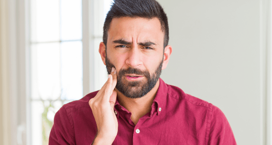 Man in need of emergency dentistry holding jaw