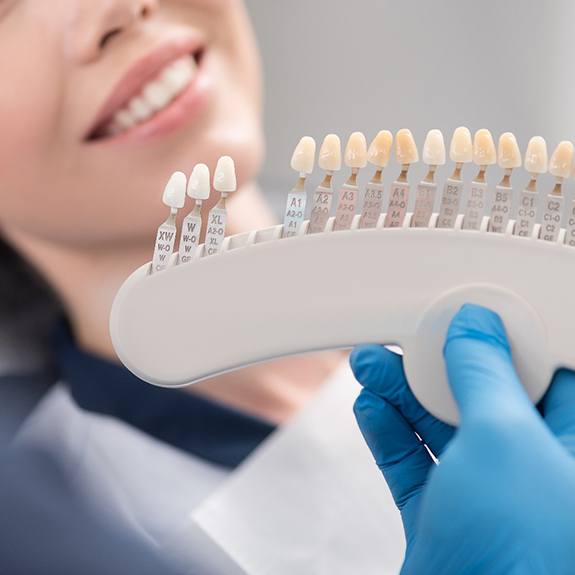 Dentist holding up veneers shades to patient's mouth