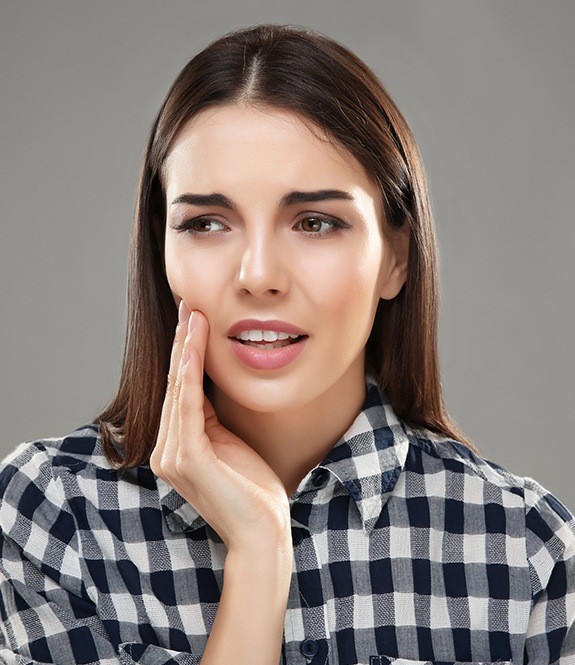 Young woman in need of wisdom tooth extraction holding jaw