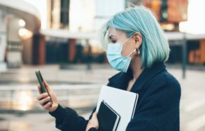 person calling their dentist in Lancaster to schedule an appointment while wearing a mask