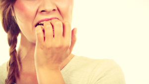 woman biting nails from dental anxiety