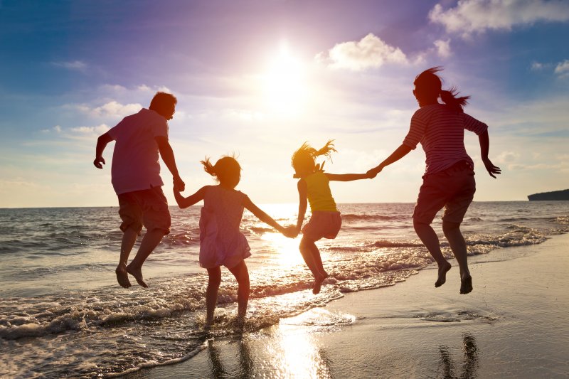 family jumping together on the beach during summer vacation