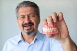 a patient holding their dentures in Lancaster